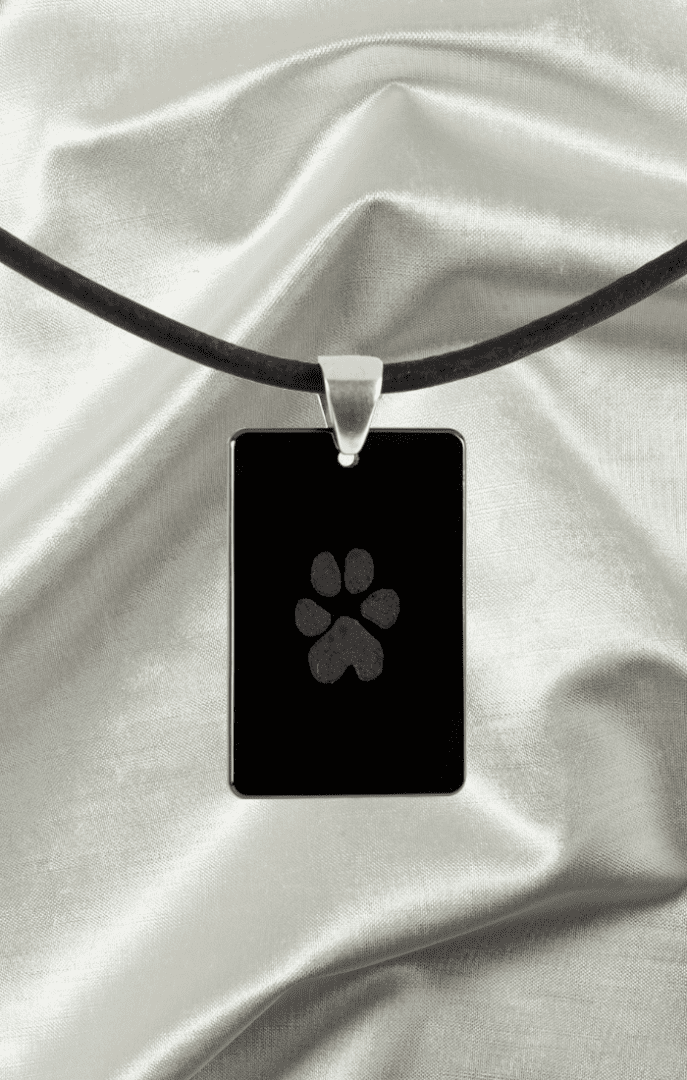 A black necklace with a black paw print on it.