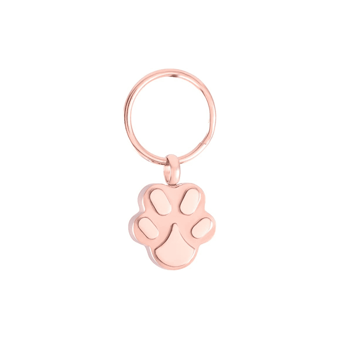 A rose gold paw print charm on a white background.