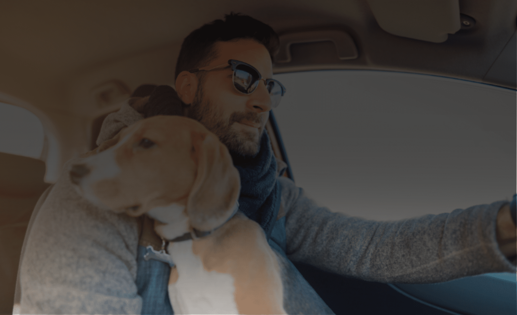 A man driving a car with a dog in the back seat.